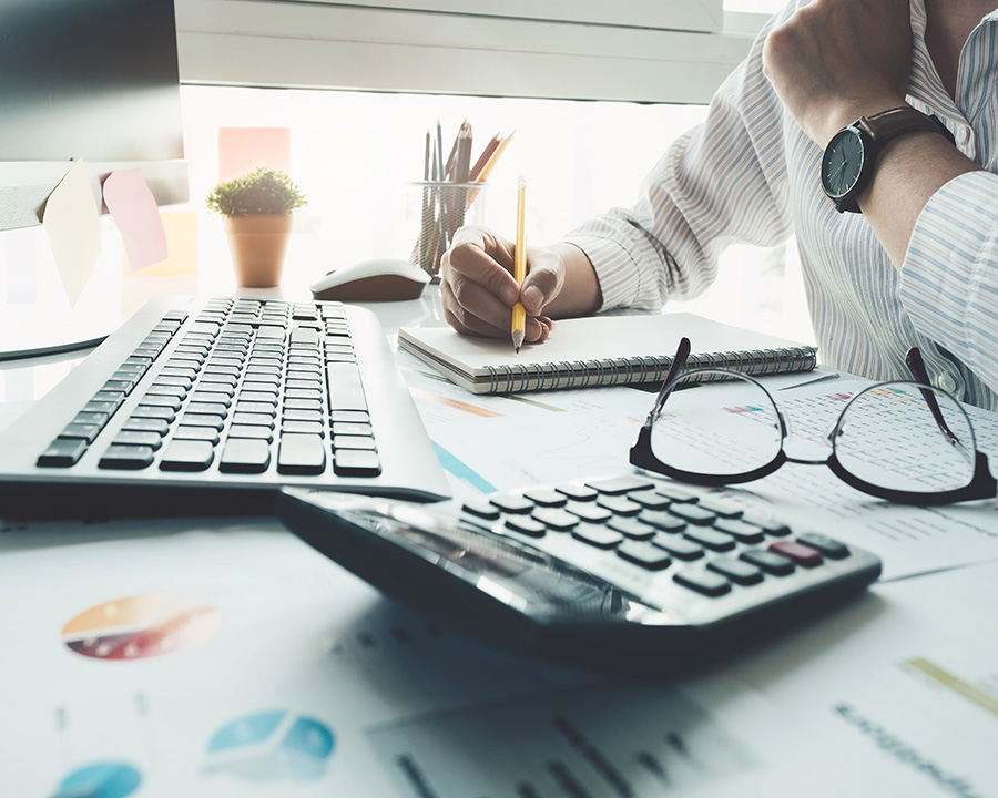 Person working on finances at a desk with calculator and graphs after financial coaching